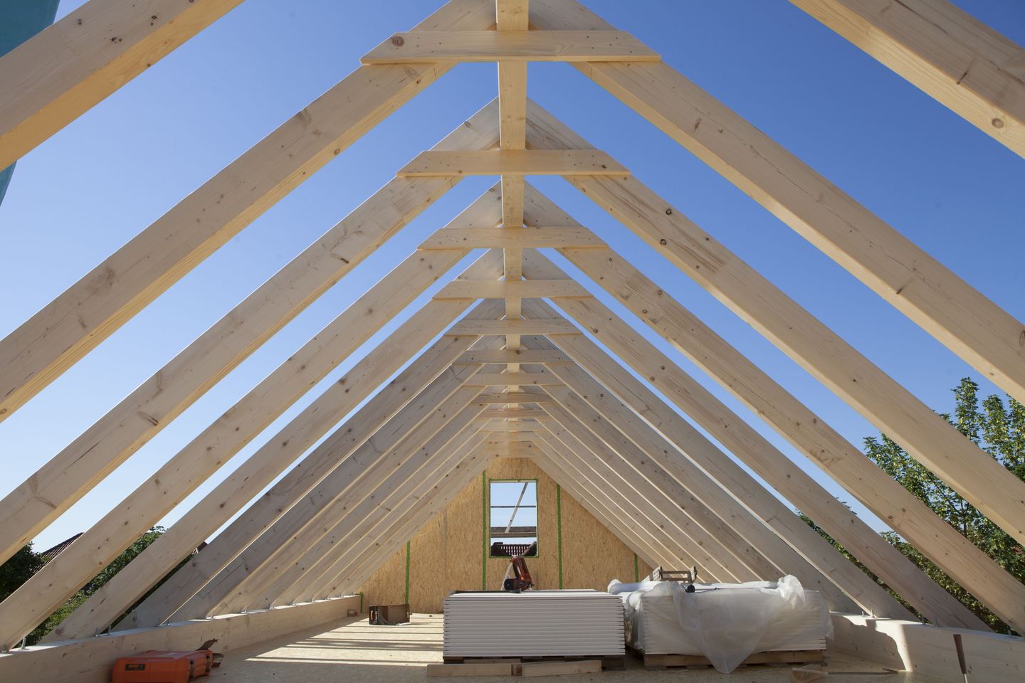 Offener Dachstuhl aus Holz vor blauem Himmel